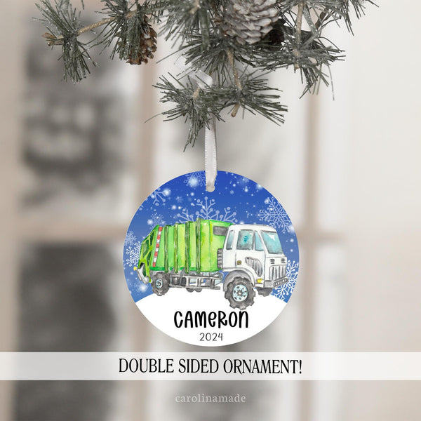 This Christmas ornament features a green garbage truck with snow background. it is personalized at the bottom with your name and year.
