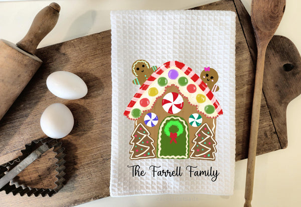 This white waffle weave towel features a fun gingerbread house and is personalized at the bottom with your family name.