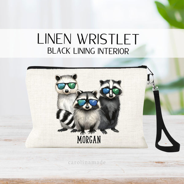 This linen lined zipper pouch features 3 raccoons with blue and green sunglasses. The bottom is personalized with your name.