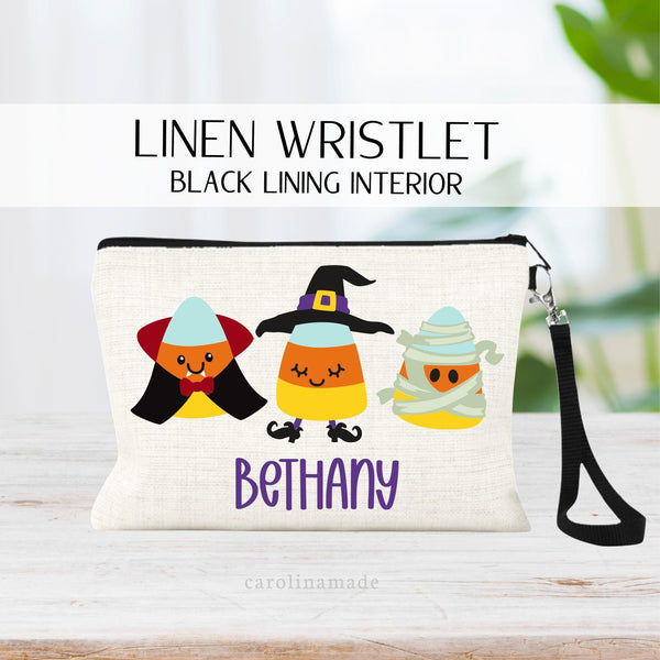 this linen wristlet features three candy corn in costumes. a Dracula, a witch and a mummy. It is personalized at the bottom with your name.