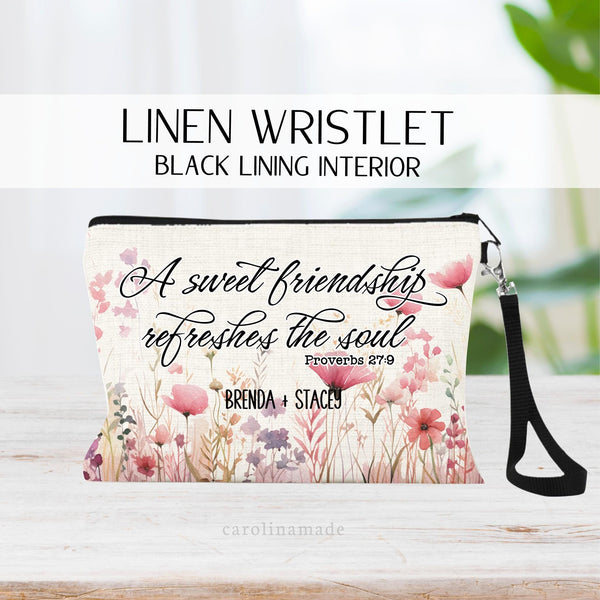 This linen wristlet says A sweet friendship refreshes the soul in a beautiful script font. With Proverbs 27:9 Under it. personalize the bottom with your best friends name.  The background shows watercolor pink wildflowers.