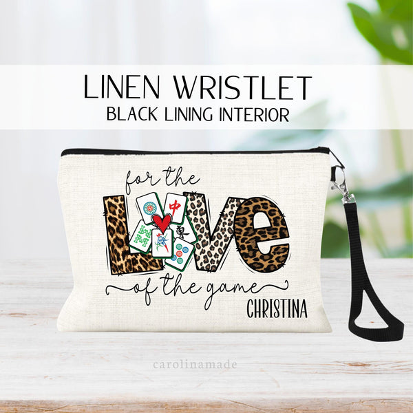 This linen wristlet features the design For the Love of the game with Mahjong cards in the center for the O in Love. It is personalized in the corner with your name.