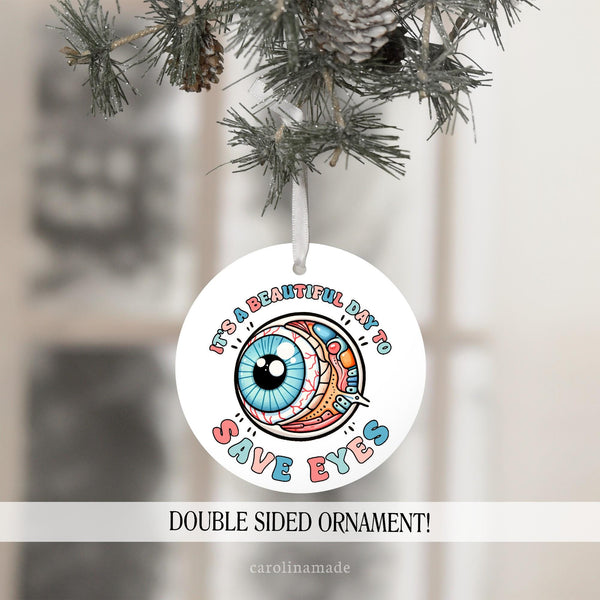 This Christmas ornament features an eye design that says It's a beautiful day to save eyes. Personalize the back with your custom text.