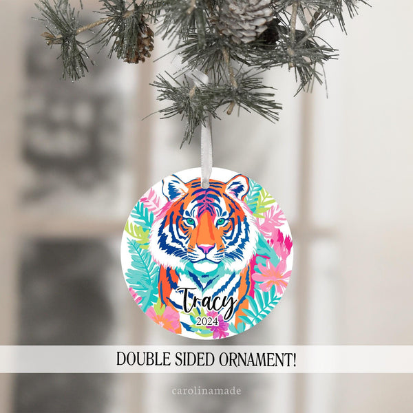 This ornament features bright colorful preppy tiger design with flowers and leaves. It is personalized at the bottom with your name and the year.