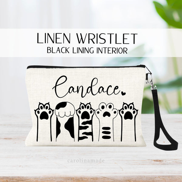 Linen zipper pouch with black cat paws in a row and is personalized at the top with a name.