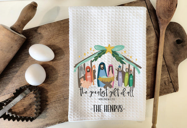 This white waffle weave towel features a manger scene and the text says the greatest gift of all. Matthew 1 21. The bottom is optional personalization with your family name.