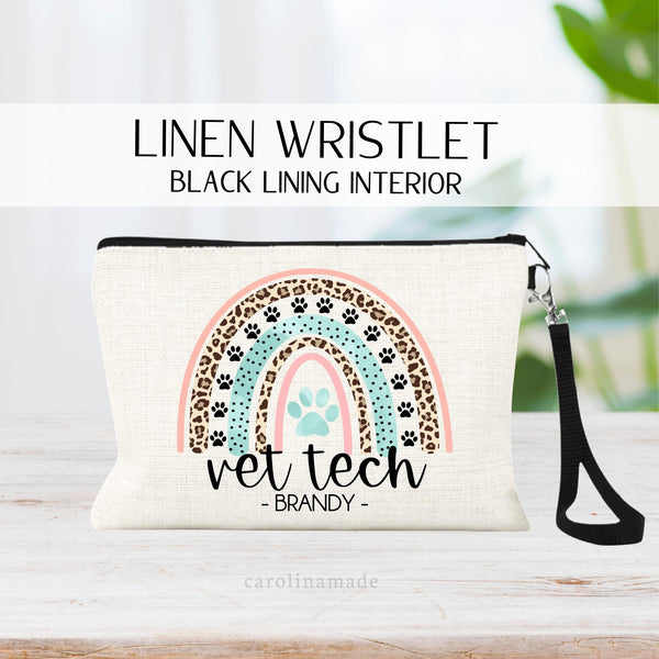 Personalized linen wristlet makeup bag with strap with a rainbow design that has paw prints in it and says vet tech and your name under the rainbow!