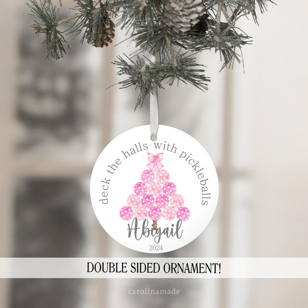 This ornament features a pink christmas tree made from pickleballs with a pink coquette bow on top. It is personalized at the bottom with your name and the year.