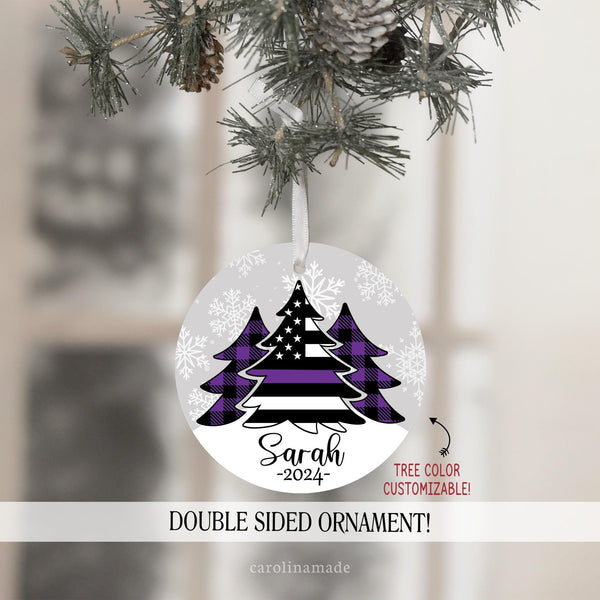 This ornament features gray snowy background with three Christmas trees in the center. Two with purple plaid. And the center large tree is a flag with a thin purple line for security. It is personalized at the bottom with your name and the year.