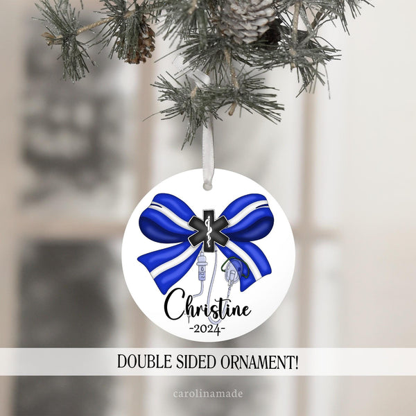 This white Christmas ornament features a large bow in paramedic colors with the emergency cross, iv and medical equipment. It is personalized at the bottom with EMT name and the current year.