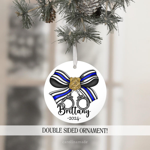 This ornament features a large bow in police colors with thin blue line and a police badge in the center that says back the blue. There are hand cuffs hanging from the bow. Your name is personalized at the bottom with the year.