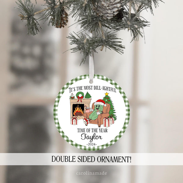 This Christmas Ornament features a fun Pickle design with a pickle on a chair in front of the fireplace with Christmas Tree and gifts and hot cocoa. It says It's the Most Dill-ightful time of the year. And is personalized with your name and the year.