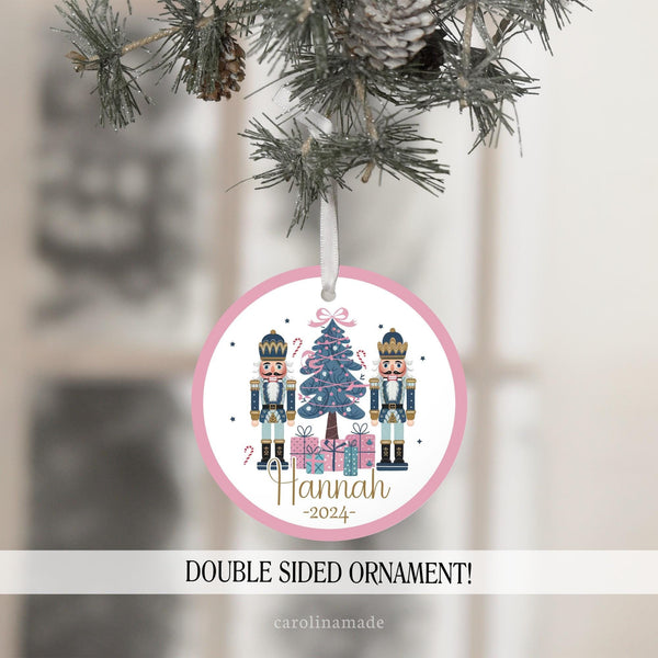 This beautiful ornament features a pink and white background with two nutcrackers and a christmas tree with presents under it. Your name is personalized at the bottom with the year.
