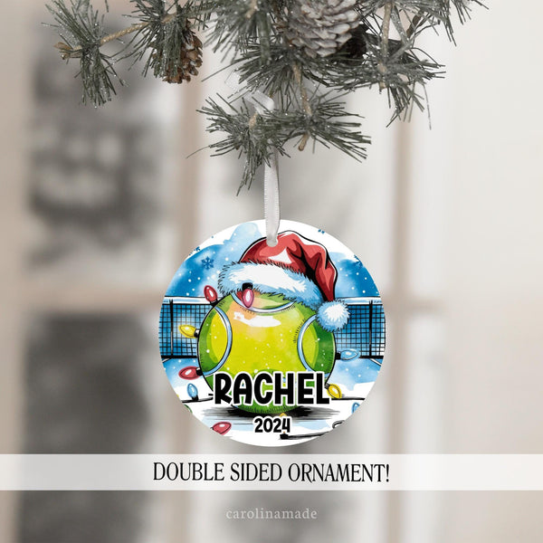 This Christmas ornament features a large tennis with a Santa hat with snowy background tennis court and Christmas lights. It is personalized with your tennis players name and the year at the bottom.