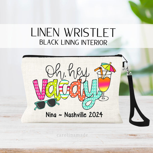 This linen wristlet features a colorful text that says Oh Hey Vacay with sunglasses and a cocktail drink. The bottom is personalized with your name, your destination and the year.