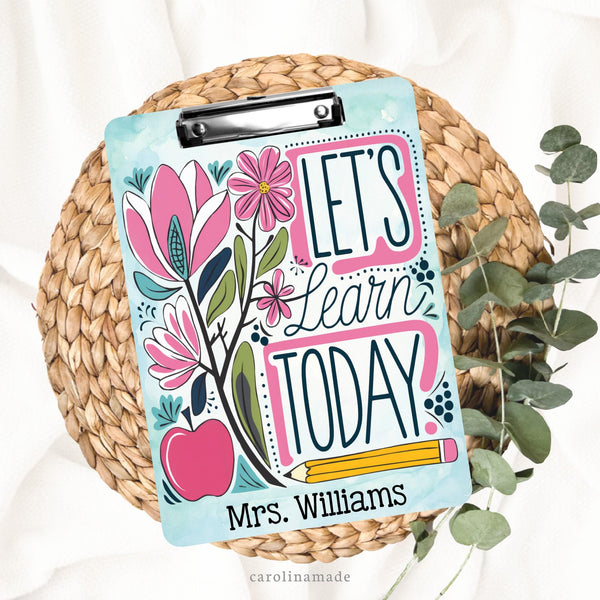 This double sided teacher clipboard has a blue watercolor background with a fun floral and apple design that says Lets learn Today with a pencil. It is personalized at the bottom with teachers name.