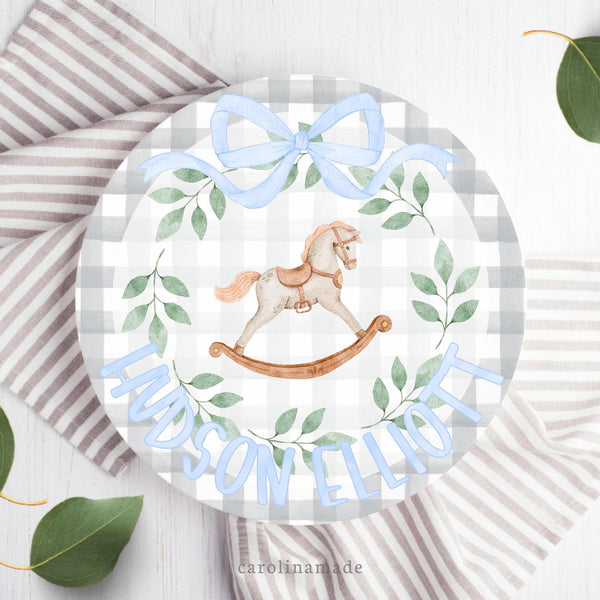 This 10 inch plate features a gray gingham background with a rocking horse in the center, a green wreath around it, a blue bow at the top and the bottom is personalized with name.