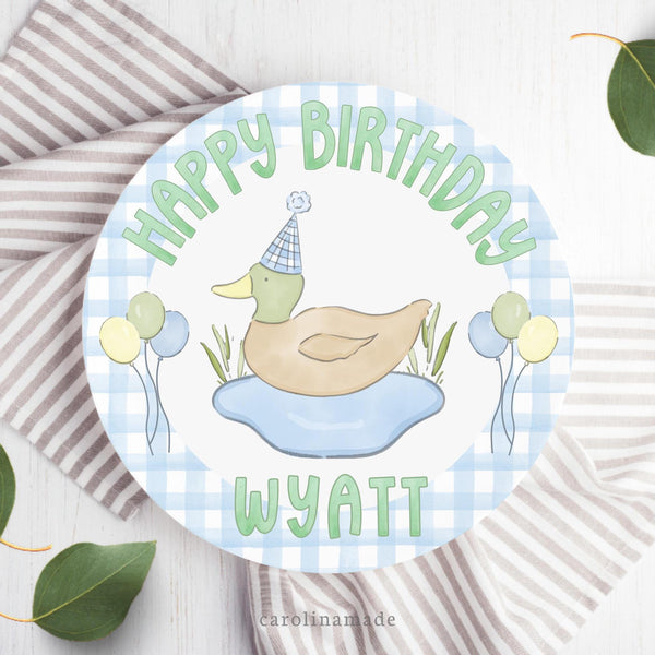 This 10 inch plate features a blue gingham background with a mallard duck wearing a birthday hat and balloons in the center. The top says happy birthday and the bottom is personalized with your childs name.