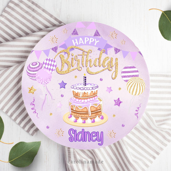 This 10 inch Happy Birthday Cake plate features a purple watercolor background with purple banner. It has purple and gold design with balloons, stars, poka dots and sparkles. The bottom is personalized with your name.