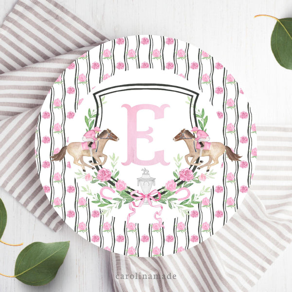 This ten inch plate features a striped floral background with a grandmillennial crest in the center with pink flowers and greenery with two derby horses on the side. The center is personalized with your initial.