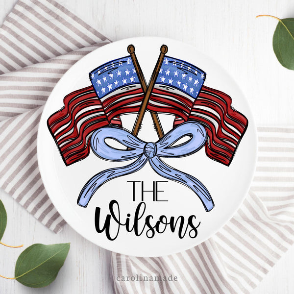 This 10 inch plate features two American flags and a blue bow. The bottom is personalized with your family name.