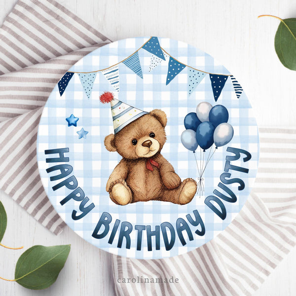 This 10 inch plate features a blue gingham background with a teddy bear  wearing a birthday hat and balloons in the center. The bottom says happy birthday and is personalized with your childs name.