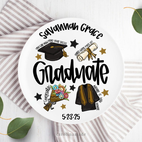 This plate features a graduation design with the graduates name personalized at the top and their graduation date at the bottom. The center has a cap, gown, flowers and a diploma. with black and gold stars.