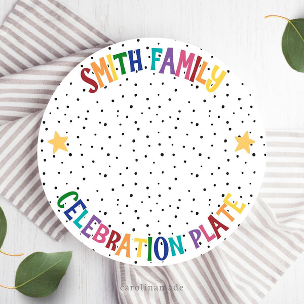 This 10 inch white plate features a modern black dot design with rainbow text that says your personalized family name at the top and celebration plate at the bottom.