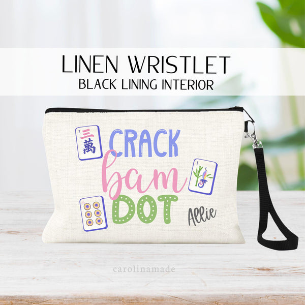 This linen zipper pouch features a colorful mahjong design. The text says crack bam dot and there are 3 mahjong cards next to the words. Your name is personalized in the bottom corner.