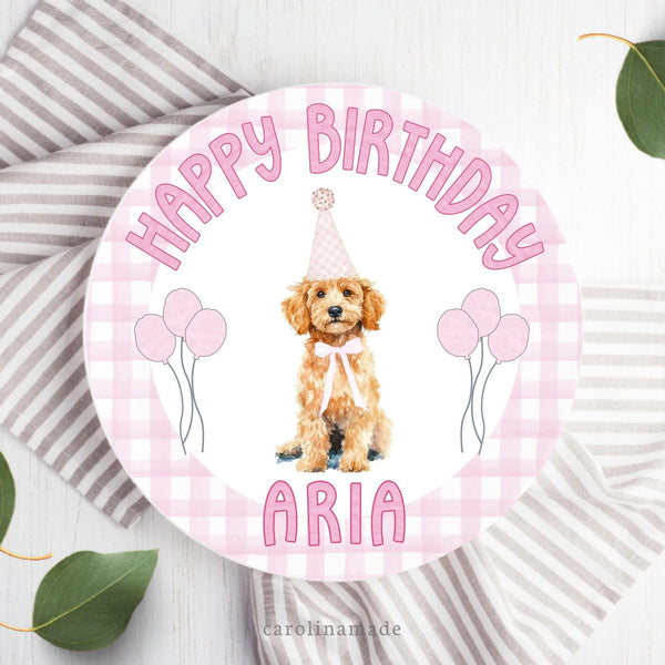 This 10 inch plate features a pink gingham background with a cream golden doddle  wearing a birthday hat and balloons in the center. The top says happy birthday and the bottom is personalized with your childs name