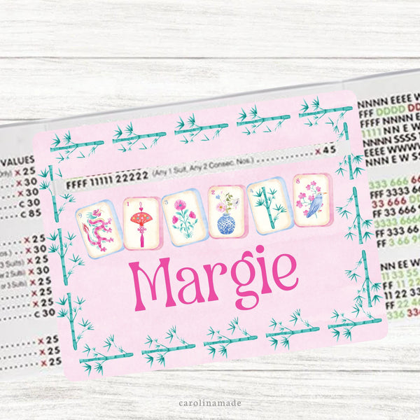This acrylic mahjong line reader features a pink background with a bamboo border and mahjong tiles in the center. Under the text is personalization with your name. Matching zipper pouch available also.