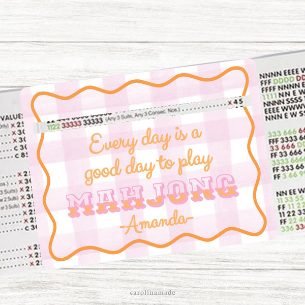 This acrylic mahjong line reader features a white and pink gingham background with orange wavy border. Pink and orange text.  The bottom is personalization with your name. Matching zipper pouch available also.