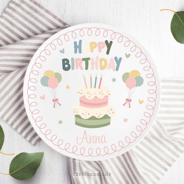 The border shows a pink doodle frame around the plate with colorful text in the center that says happy birthday, has a cake, balloon, stars and hearts. The bottom is personalized with your name.