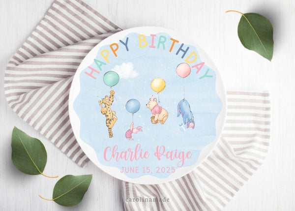 This ten inch plate features a light blue watercolor background. The top says happy birthday with a classic pooh and friends art in the center holding balloons. The bottom is personalized with name and date of birth.