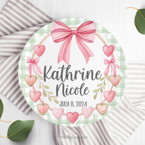 This plate features a green gingham scallop border with a pink bow at the top and pink hearts frame around the plate. The center is personalized with your childs name date of birth.